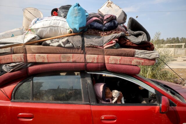 A displaced Palestinian child playes with a kitten in a car on Salah al-Din road in Nuseir