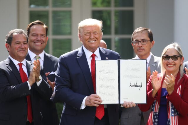 Donald Trump, shown in this July 2020 photo, holds up an executive order he signed during