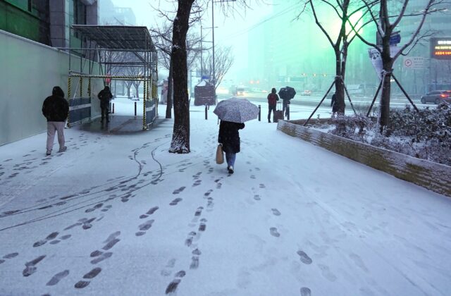 Footprints are seen as pedestrians walk along a snow-covered street during snowfall in cen