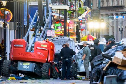 Police investigators surround the white Ford F-150 pickup truck that crashed into a work l