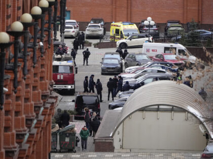 Investigators and police officers stand in the yard of an upscale residential block in Mos