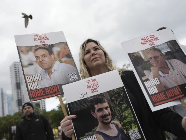 AP25039280052943 A woman holds posters with photos of Israelis hostages Eli Sharabi, Or Levy and Ohad Ben A