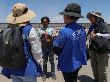 Activists from the Jesuit Refugee Service give food and water to a migrant in the border b