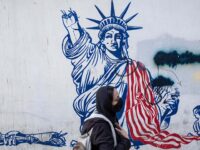 A young Iranian woman walks past an anti-U.S. mural on a wall of the former U.S. embassy i