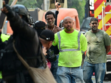 Demonstrators are detained by riot police officers during a protest against a bill being d