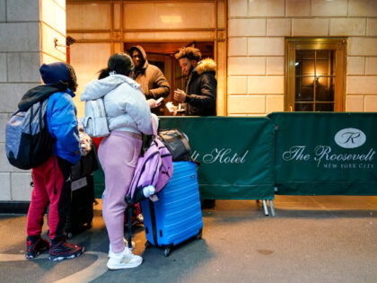 An immigrant family show their paperwork to security guards at the Roosevelt Hotel, Tuesda