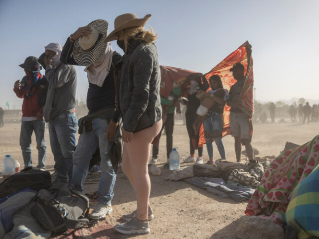 Immigrants from Venezuela cover up during a dust storm at a makeshift immigrant camp locat