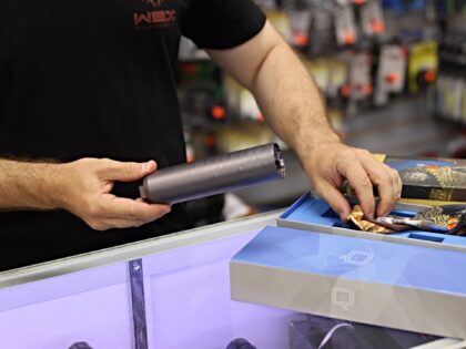 DELRAY BEACH, FLORIDA - MARCH 24: Ian Brabender helps a customer buying a gun suppressor a