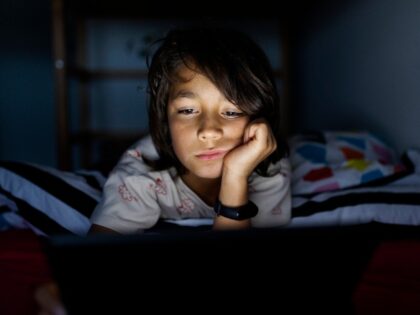 a tween boy using his tablet in bed