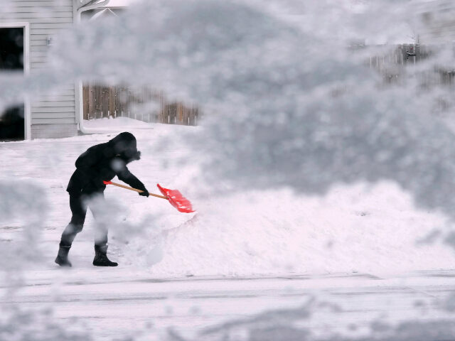 A local resident shovels snow off the end of a driveway, Thursday, Dec. 22, 2022, in Urban