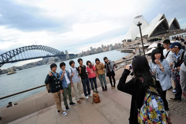 A group of Japanese tourists pose for photographs at Sydney Harbour in 2012. Today around