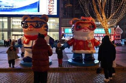 People have their pictures taken with mascots of the Asian Winter Games in Harbin