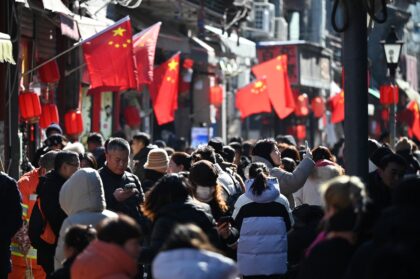 People walk below Chinese flags in an alley near a popular shopping street during the Luna