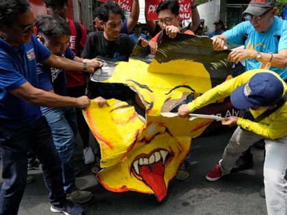 Activists tear a caricature of Chinese President Xi Jinping during a protest near the Chin