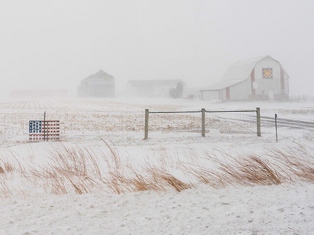 An American flag is mounted on a fence at a farm on U.S. Highway 20 during a blizzard near