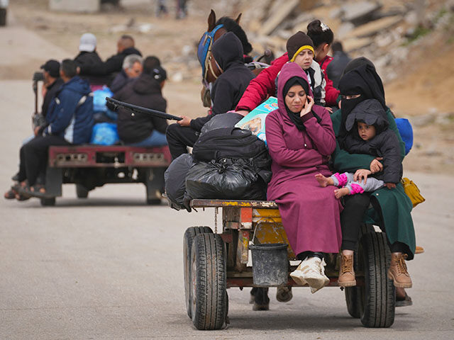 Displaced Palestinians, carrying their belongings and other items, move between southern a