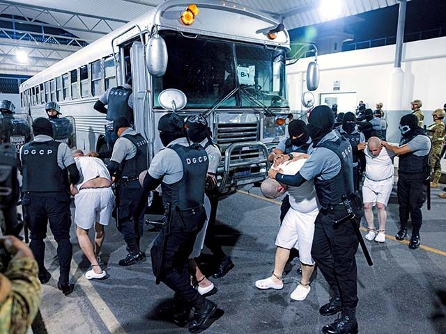 In this photo provided by El Salvador's presidential press office guards transfer deportee