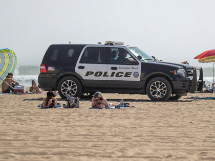 Huntington Beach police patrol the beach near the pier as thousands of beach-goers enjoy a