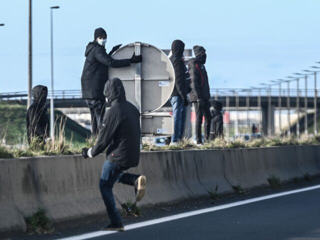 Migrants run across the A 16 motorway in an attempt to climb into the back of lorries boun