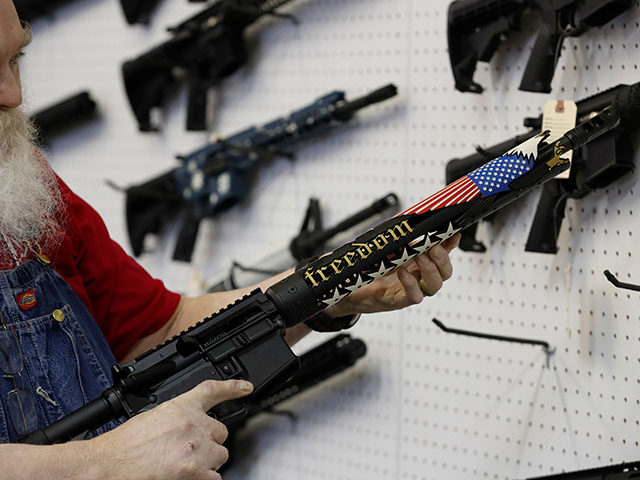 A salesperson holds a custom AR-15 rifle with "Freedom" written on it at a store in Orem,