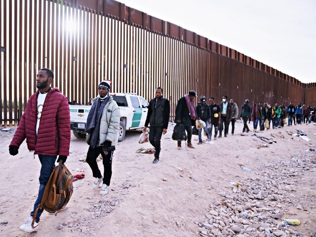 Migrants walk beside the US-Mexico border fence in Lukeville, Arizona, US, on Monday, Dec.