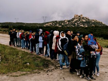 Migrants wait to be transported for asylum claim processing at the US-Mexico border in Cam