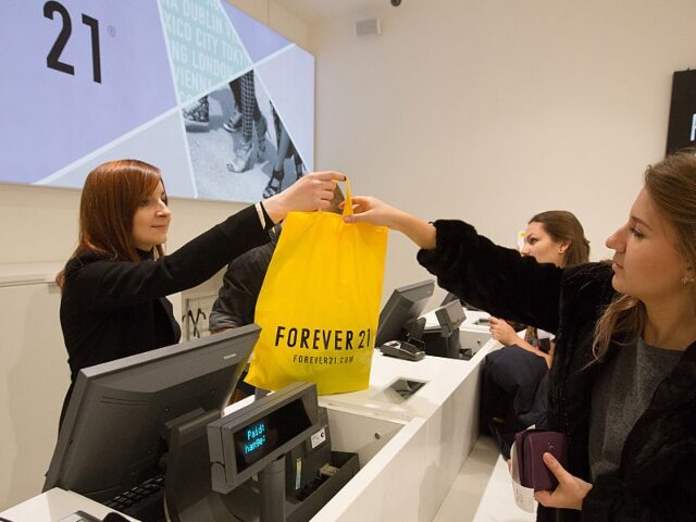 GettyImages-460094692 A customer collects a yellow plastic bag of purchases from an employee at the service coun