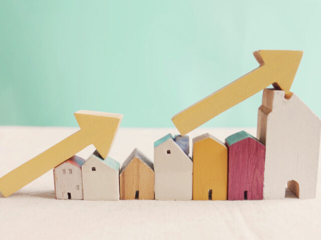 Wooden houses with yellow arrows up. housing boom, property market growing, high demand fo