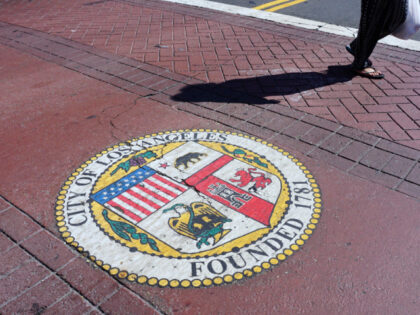 A woman crosses a street in front of City Hall in Los Angeles, California on August 22, 20