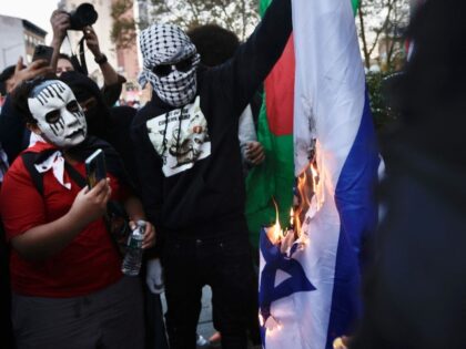 Demonstrators burn a Israeli flag during a demonstration in support of Palestinians outsid