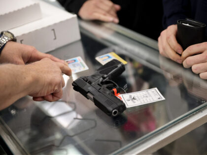 TINLEY PARK, ILLINOIS - APRIL 08: A customer purchases a gun at Freddie Bear Sports on Apr