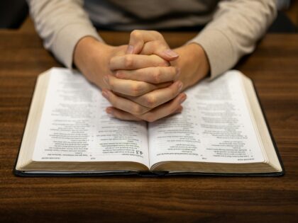 A person praying over a Bible