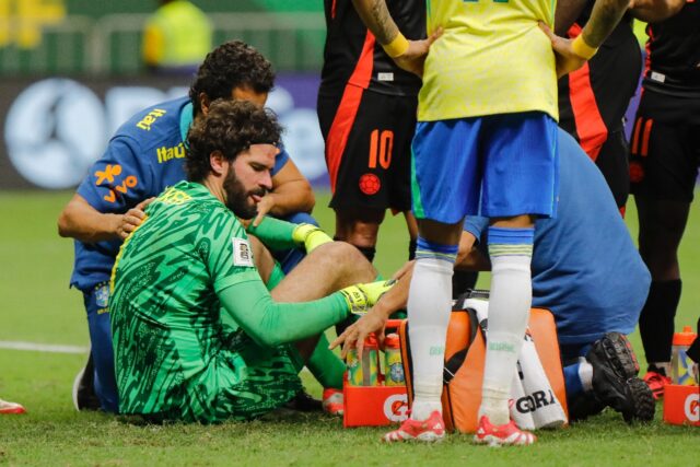 Alisson Becker receives treatment on the pitch after his collision with Colombia defender
