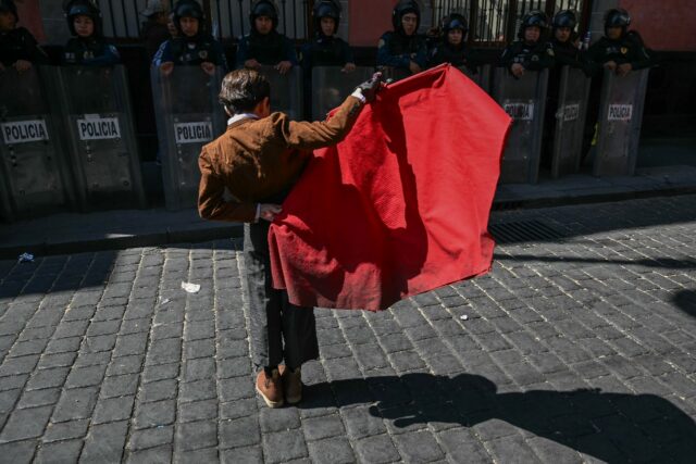 A young bullfighter performs in front of riot police during a protest against moves to ban