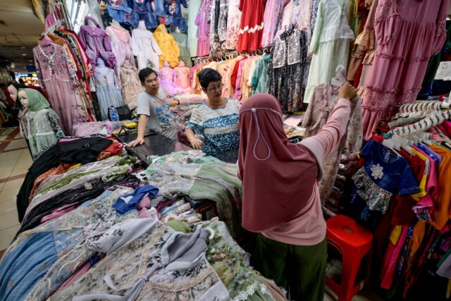A customer chooses clothes she wants to purchase at Tanah Abang Market in Jakarta