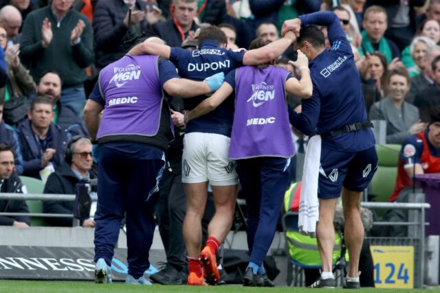 France scrum-half Antoine Dupont (C) is helped from the field in Dublin