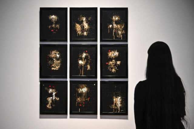 A person looks at AI artwork created by Pindar Van Arman's Emerging Faces at a preview for