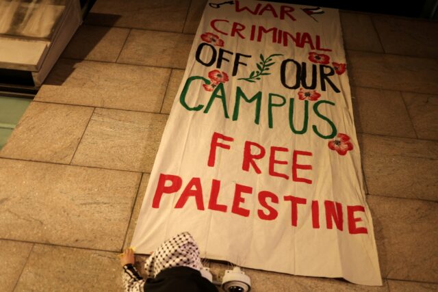 Pro-Palestinian protesters hang a banner as they gathered outside the campus of Columbia U