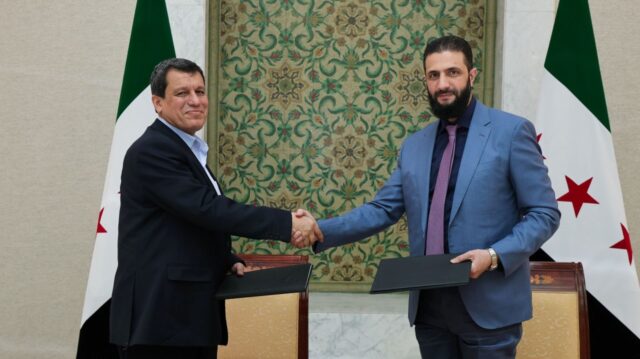 Syrian interim president Ahmed al-Sharaa (R) shakes hands with Syrian Democratic Forces (S