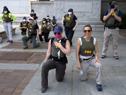 Federal Bureau of Investigation (FBI) officers take a knee with demonstrators, as they mar