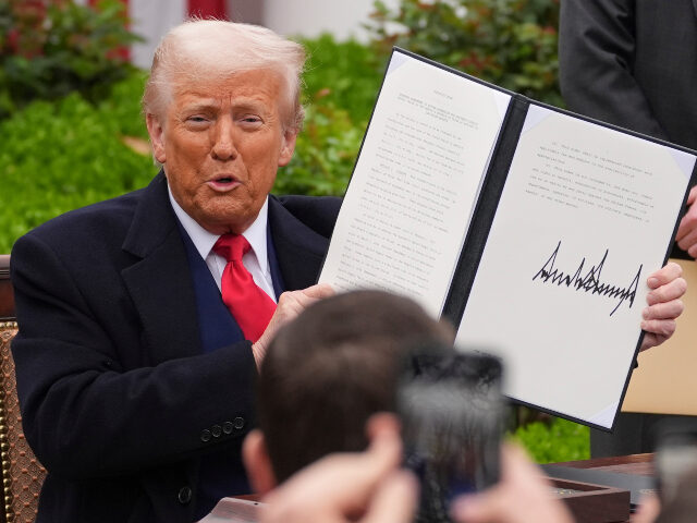 President Donald Trump holds a signed executive order during an event to announce new tari