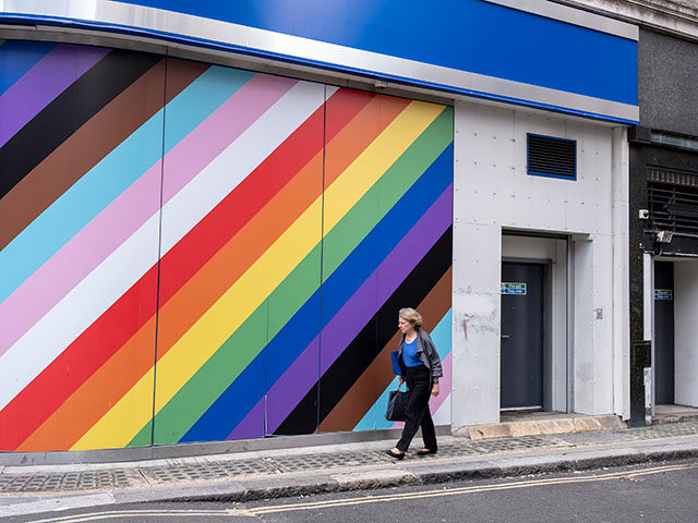 People interact with a large wall outside a high street bank emblazoned with the colours o