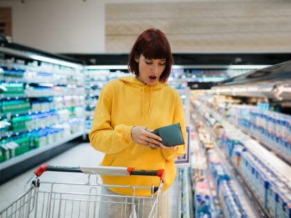 Young adult woman with red hair buying groceries in a local supermarket, expressing a stat