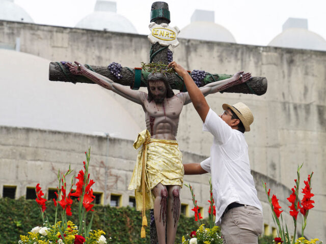 A man places a crown of thorns on a statue of Jesus Christ during a Good Friday procession