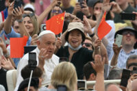 A woman waves China's flags as Pope Francis waves to the crowd from the popemobile during