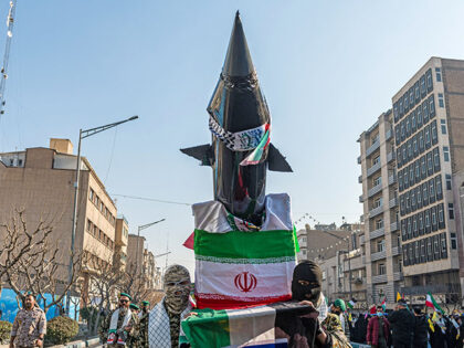 Masked Basiji militants carry a mockup of a missile with Iran's flag during a parade of an