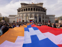 People carry a large Artsakh flag in front of the National Opera House in Yerevan, Armenia