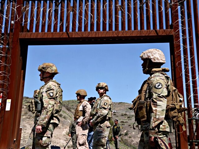 SAN YSIDRO, CA - MARCH 21, 2025 - - Members of the U.S. military are framed by an open ga