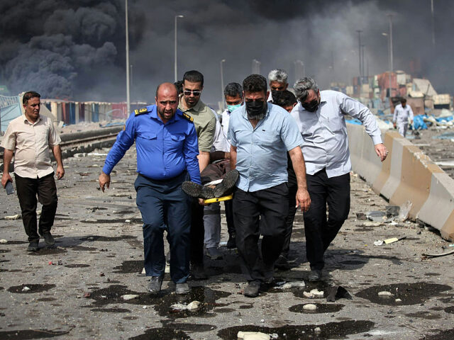 People transport an injured man along a devastated boulevard following an explosion at the