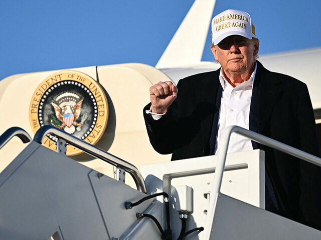 US President Donald Trump raises a fist as he steps off Air Force One upon arrival at Join